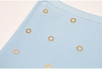 Close-up detail of blue knit fabric with gold crystal circle embellishments