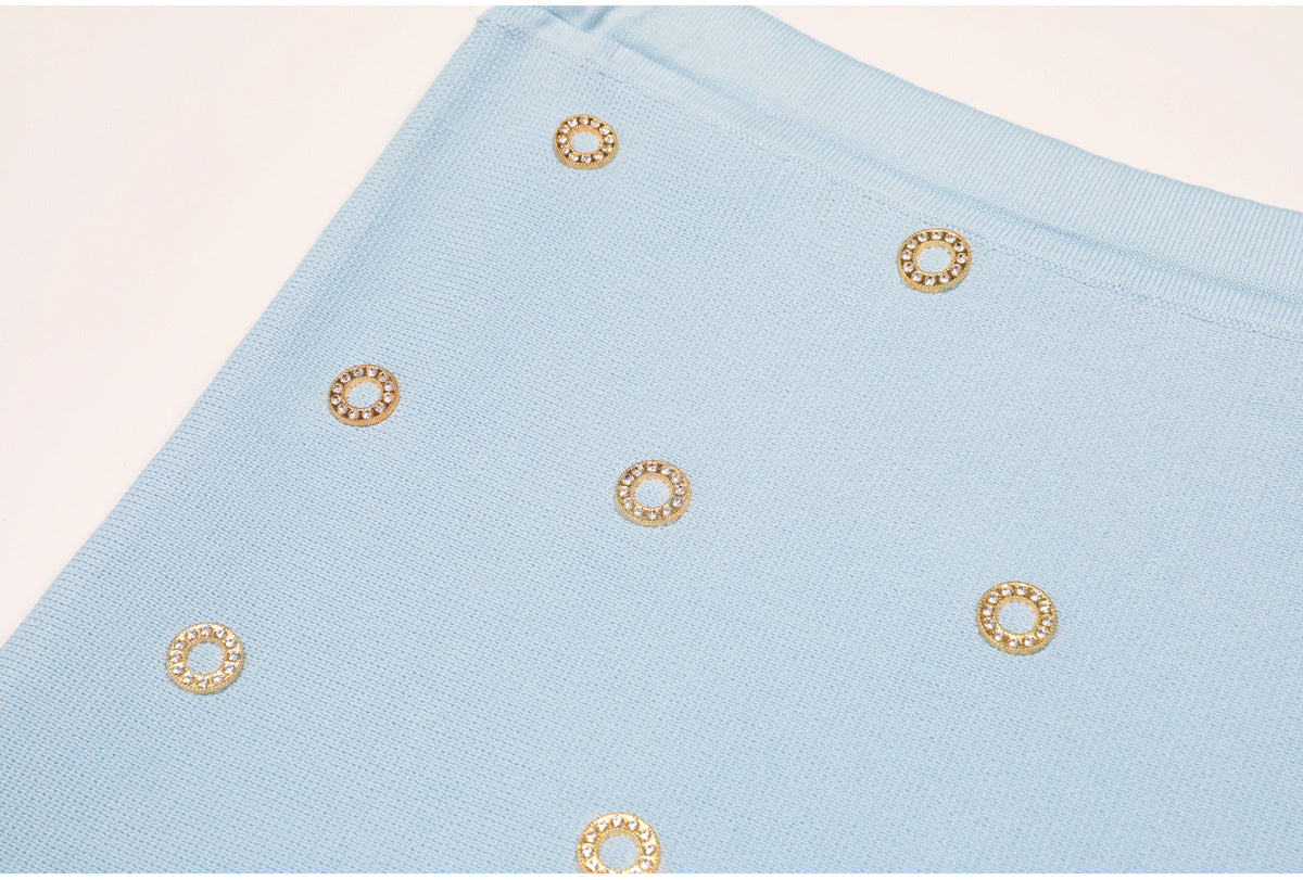 Close-up detail of blue knit fabric with gold crystal circle embellishments