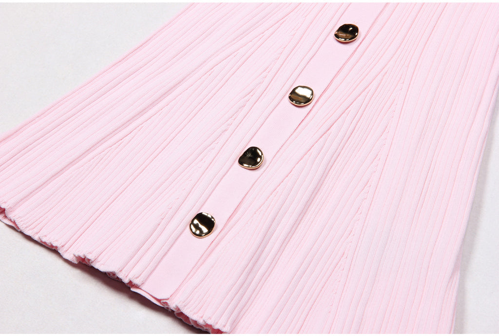 Close-up of pink dress hem with pleats and metallic buttons