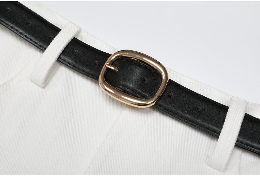 Close-up of gold buckle and black belt on white fabric