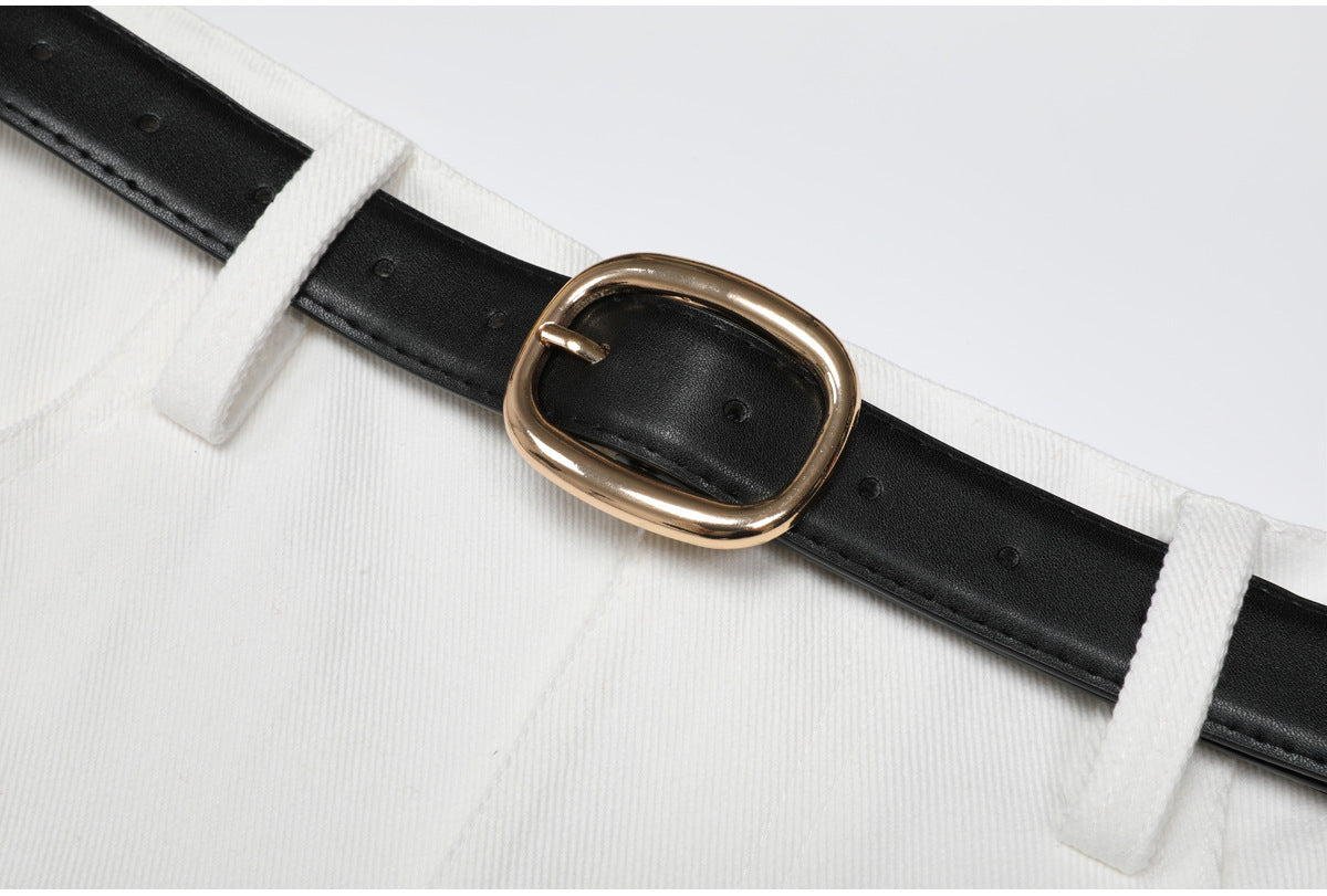 Close-up of gold buckle and black belt on white fabric