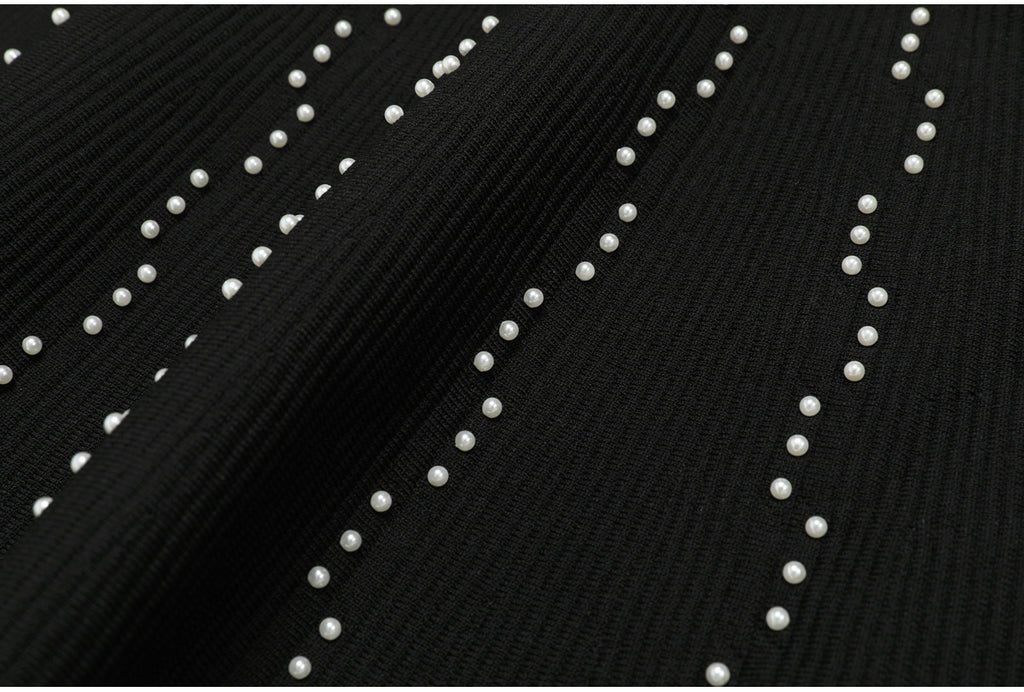 Textured view of black knit fabric with scattered pearl embellishments