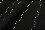 Textured view of black knit fabric with scattered pearl embellishments