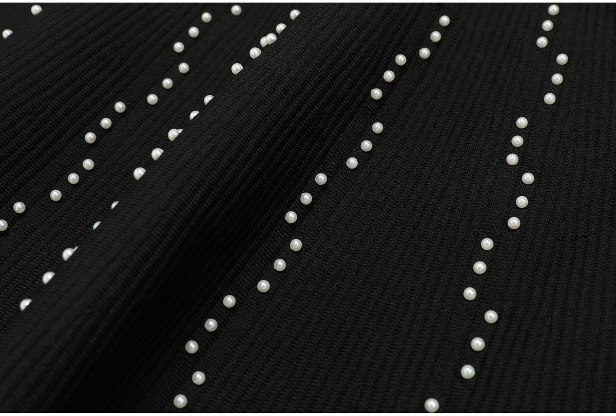 Textured view of black knit fabric with scattered pearl embellishments
